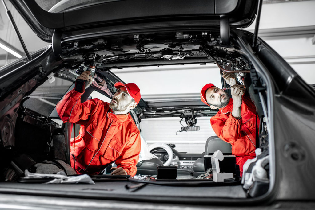 Car service workers disassembling car interior