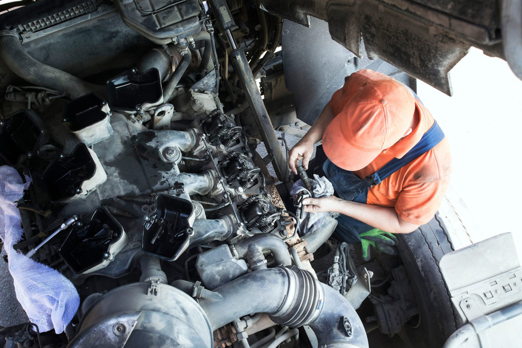 Mechanic repairs a truck. adjustment of valves of the diesel motor. Replacement nozzles.