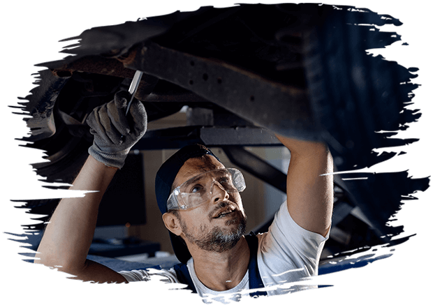 Mid adult mechanic repairing undercarriage of a car in auto repair shop.