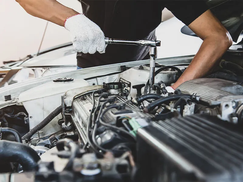 lose-up hand of auto mechanic using wrench to repair a car engine.