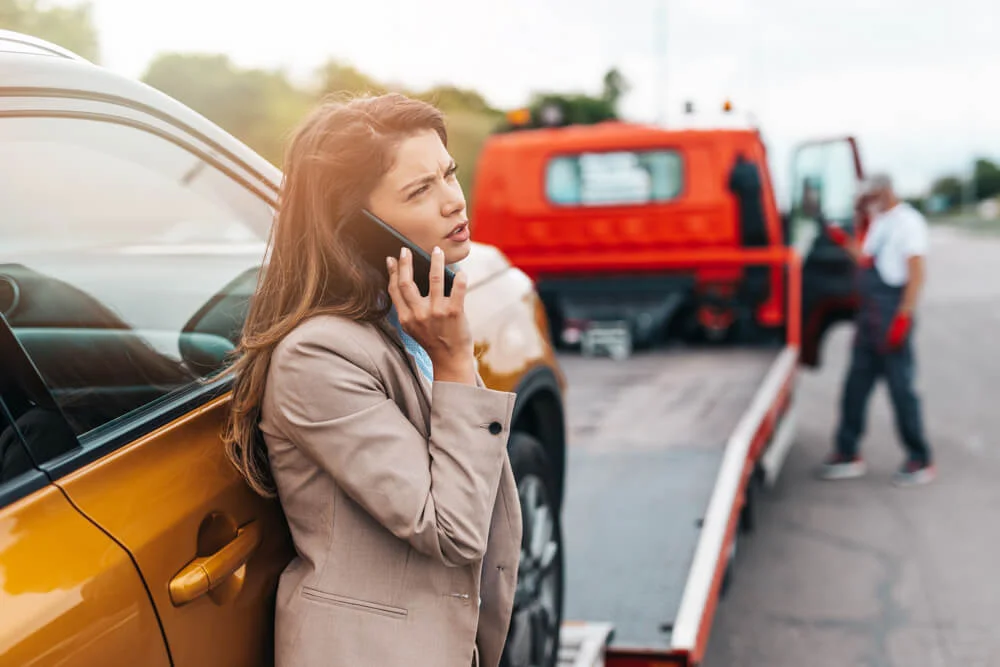 Elegant middle age business woman calling someone while towing service helping her on the road
