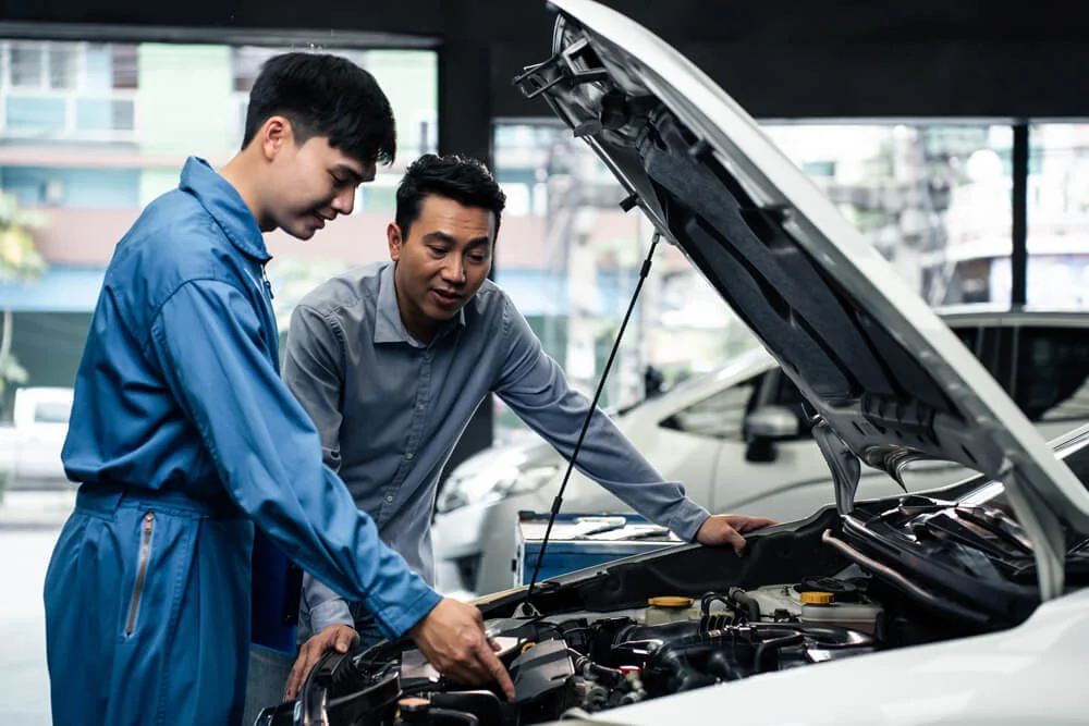 Asian automotive mechanic explain car condition to client in garage