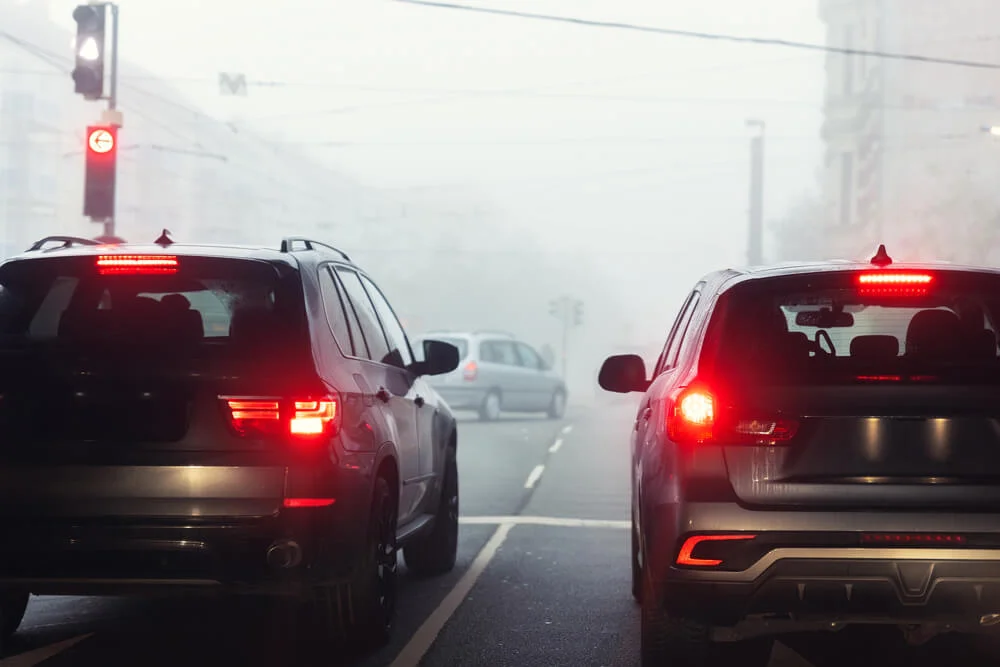 Scenic city road traffic light jam wim many cars at foggy misty rainy haze morning low poor visibility cold spring autumn season