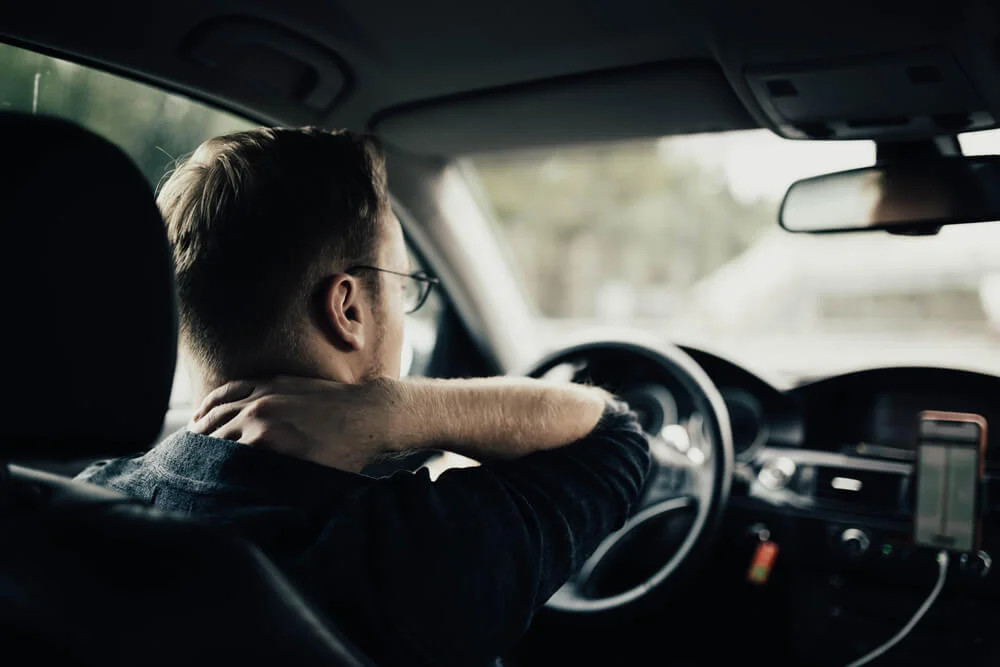 illness of the back and neck of the driver. A tired auto driver is massaging his neck on a trip.