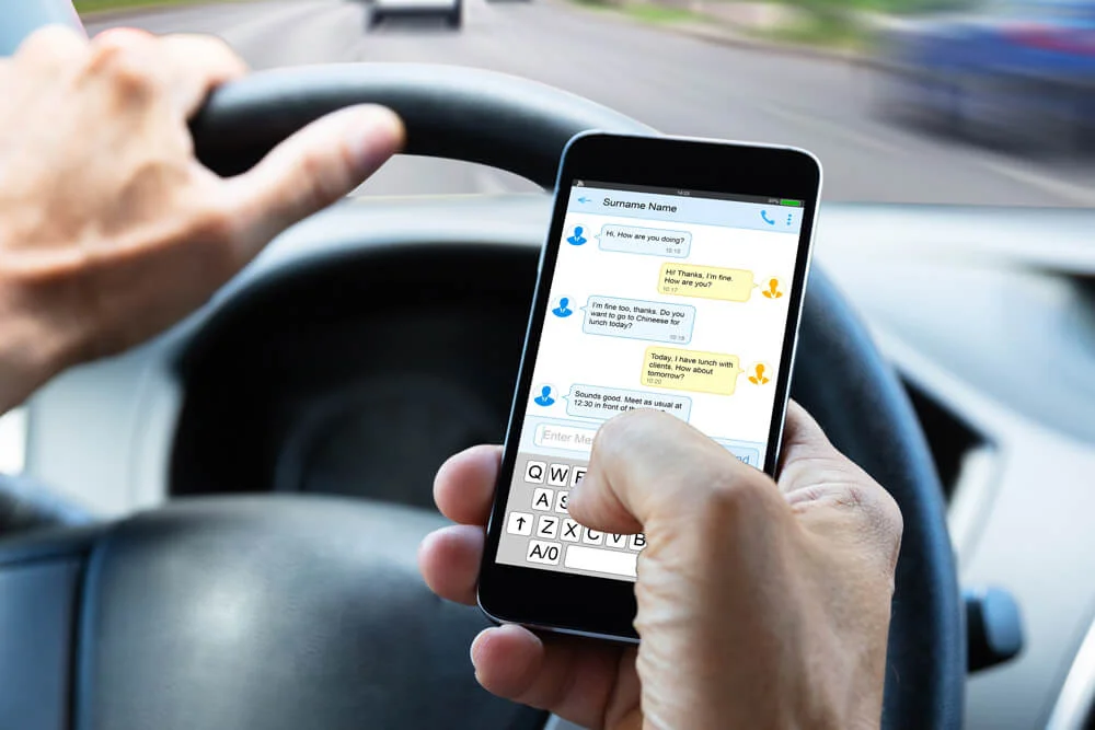 Close-up Of A Man's Hand Typing Text Message On Mobile Phone While Driving Car