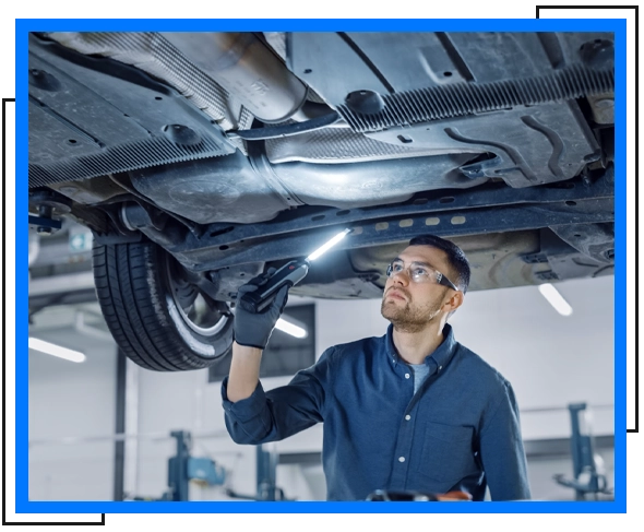 mechanic checking under car holding a light stick