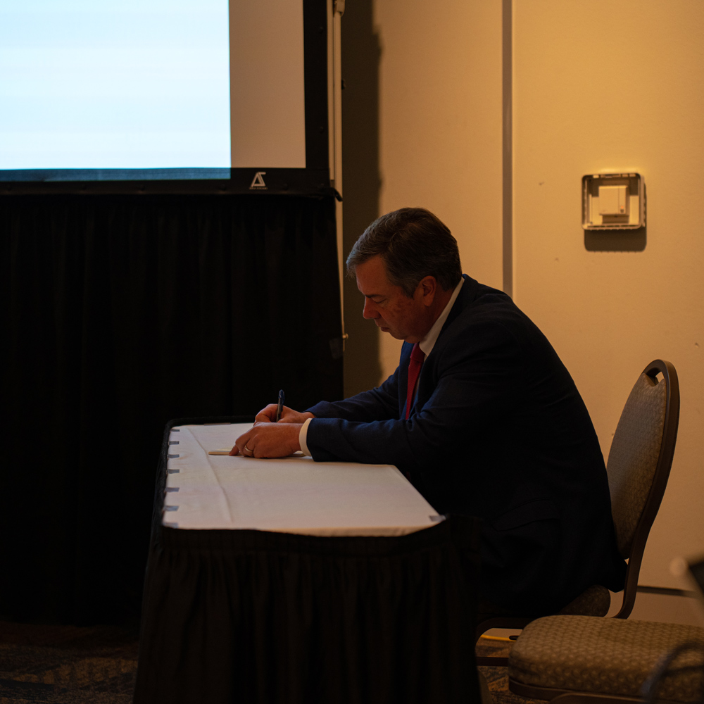 Man seated on a chair writing something down