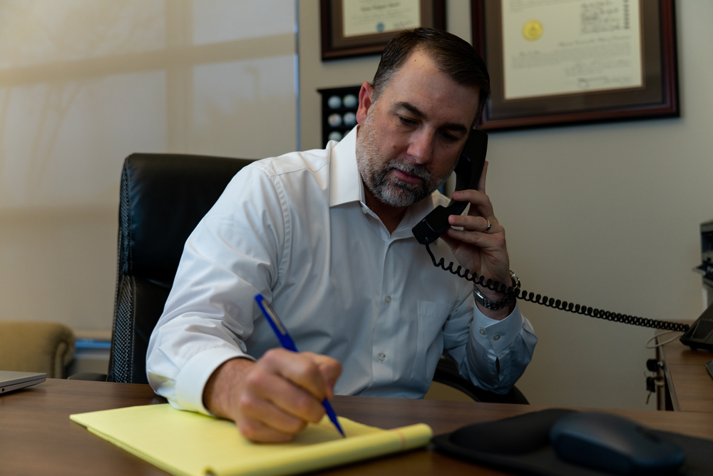 Man writing something down while talking on the phone