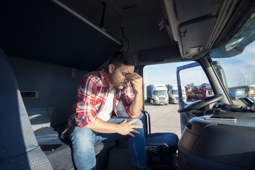 Stressed-truck-driver-rubbing-eyes-in-cab