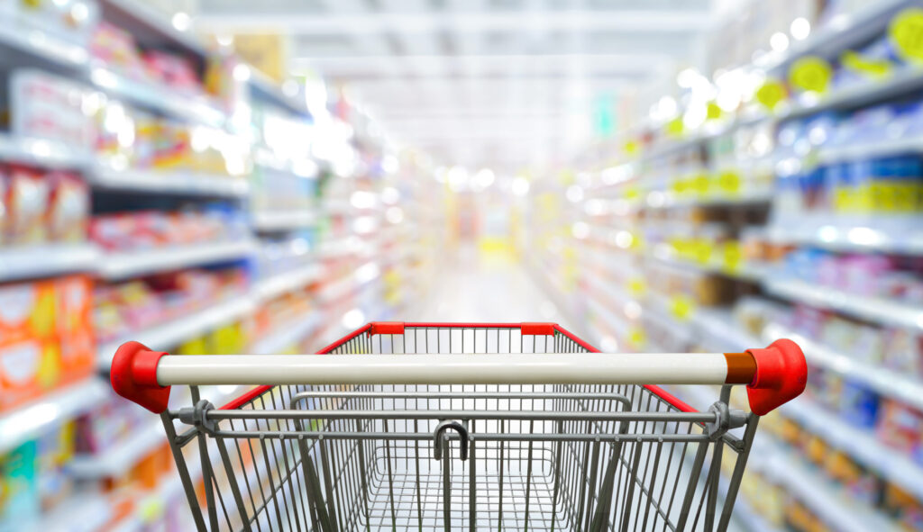 Supermarket aisle with empty red shopping cart.