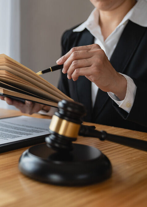 Asian female lawyer or legal advisor working on the scale of justice sitting at her desk