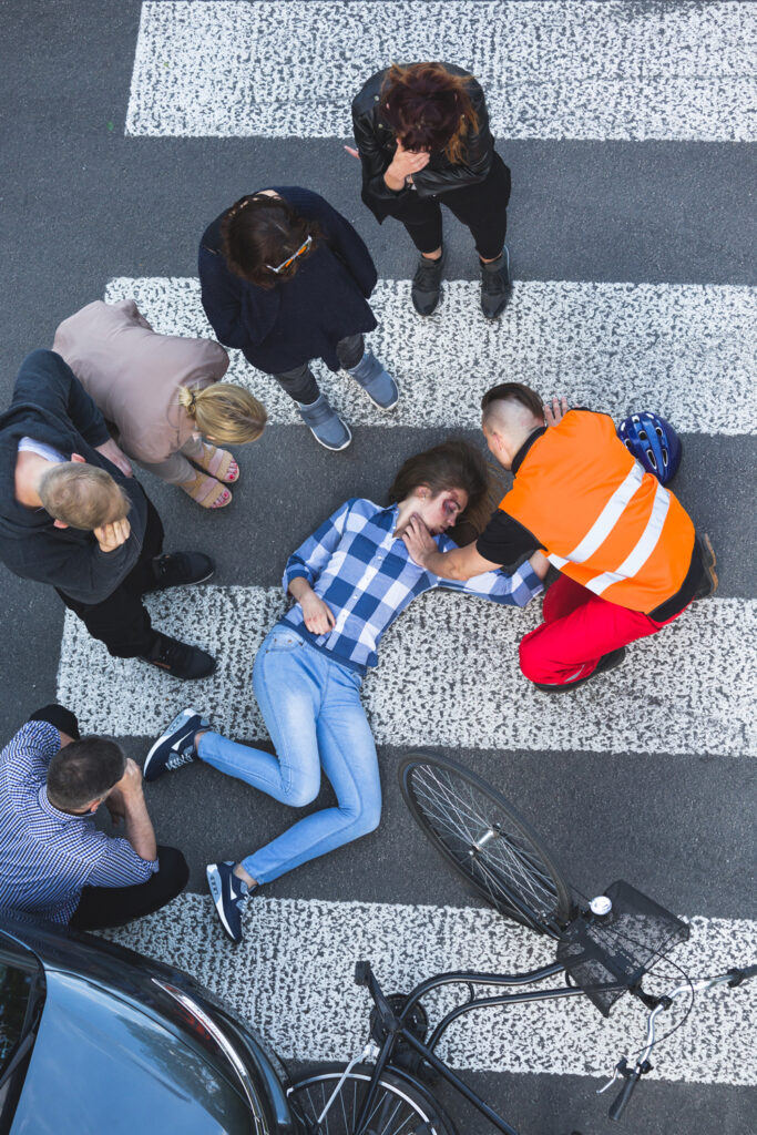 Onlookers of car crash surrounded the accident casualty lying on the road
