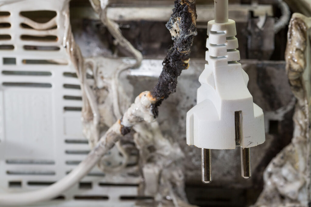Closeup of burnt cable with burnt electrical appliance