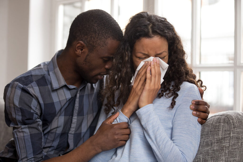Supportive african husband embracing crying wife asking for forgiveness or consoling comforting helping sharing grief or problem