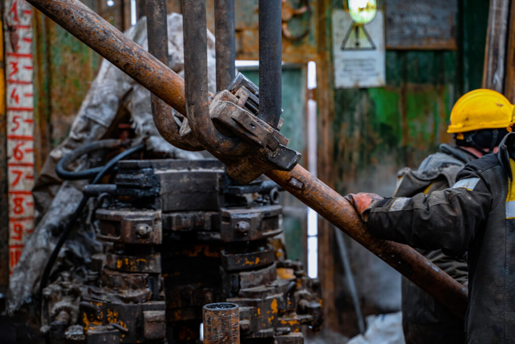 Two working drillers in a uniform, in a helmet and goggles,