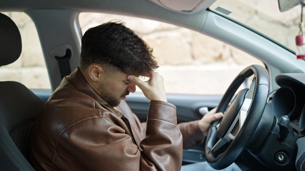 Young arab man stressed driving car at street