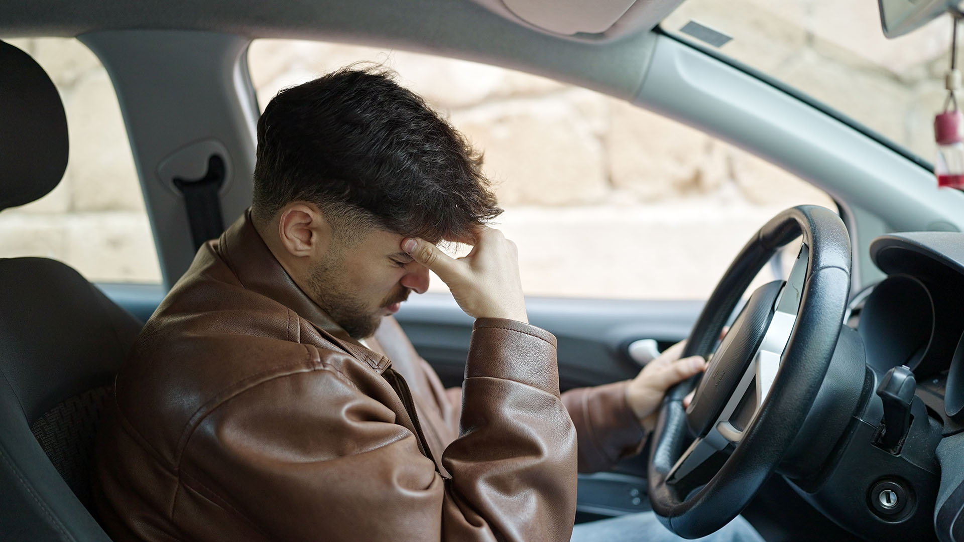 Young arab man stressed driving car at street