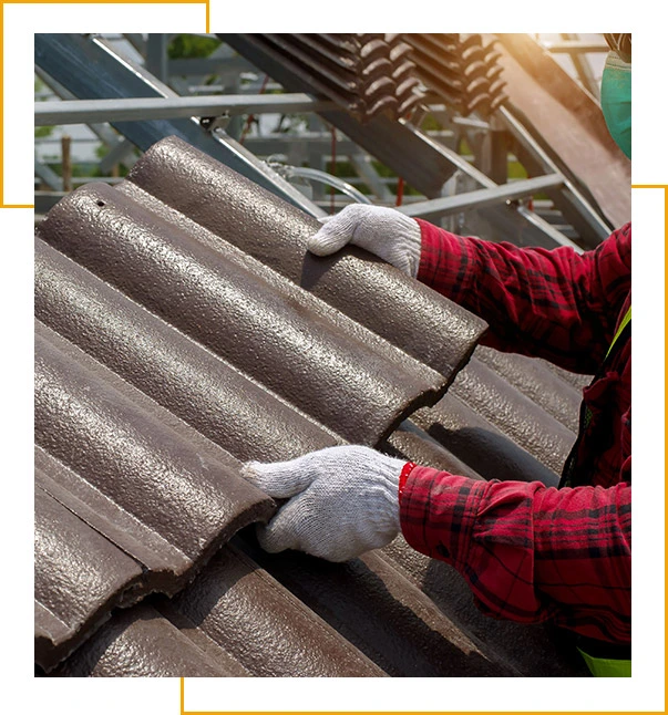 Roof repair, worker with white gloves replacing gray tiles or shingles on house with blue sky as background and copy space