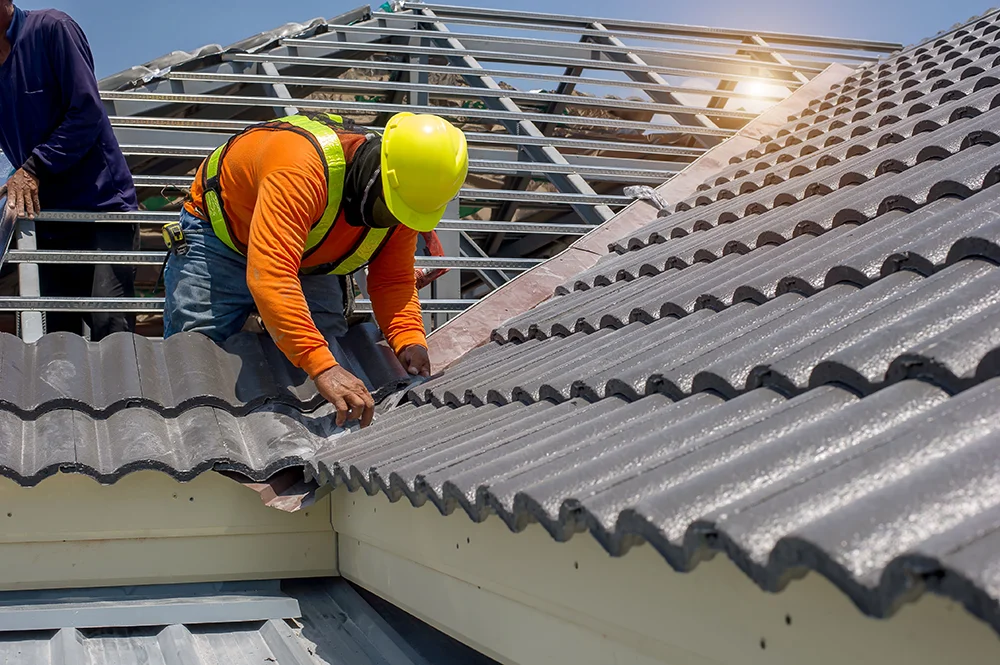 Roof repair, worker replacing gray tiles or shingles on house with blue sky as background and copy space, Roofing